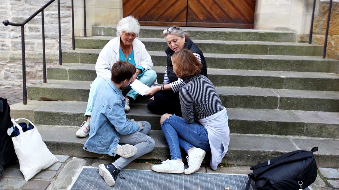 Vier Menschen unterhalten sich auf den Stufen des Doms in Münster.